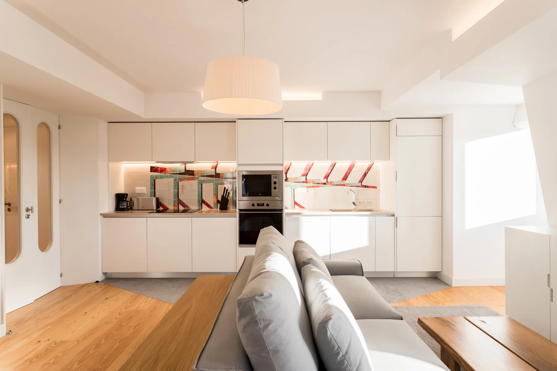 Una luminosa sala de estar se abre a una cocina moderna, con suelo de madera clara.