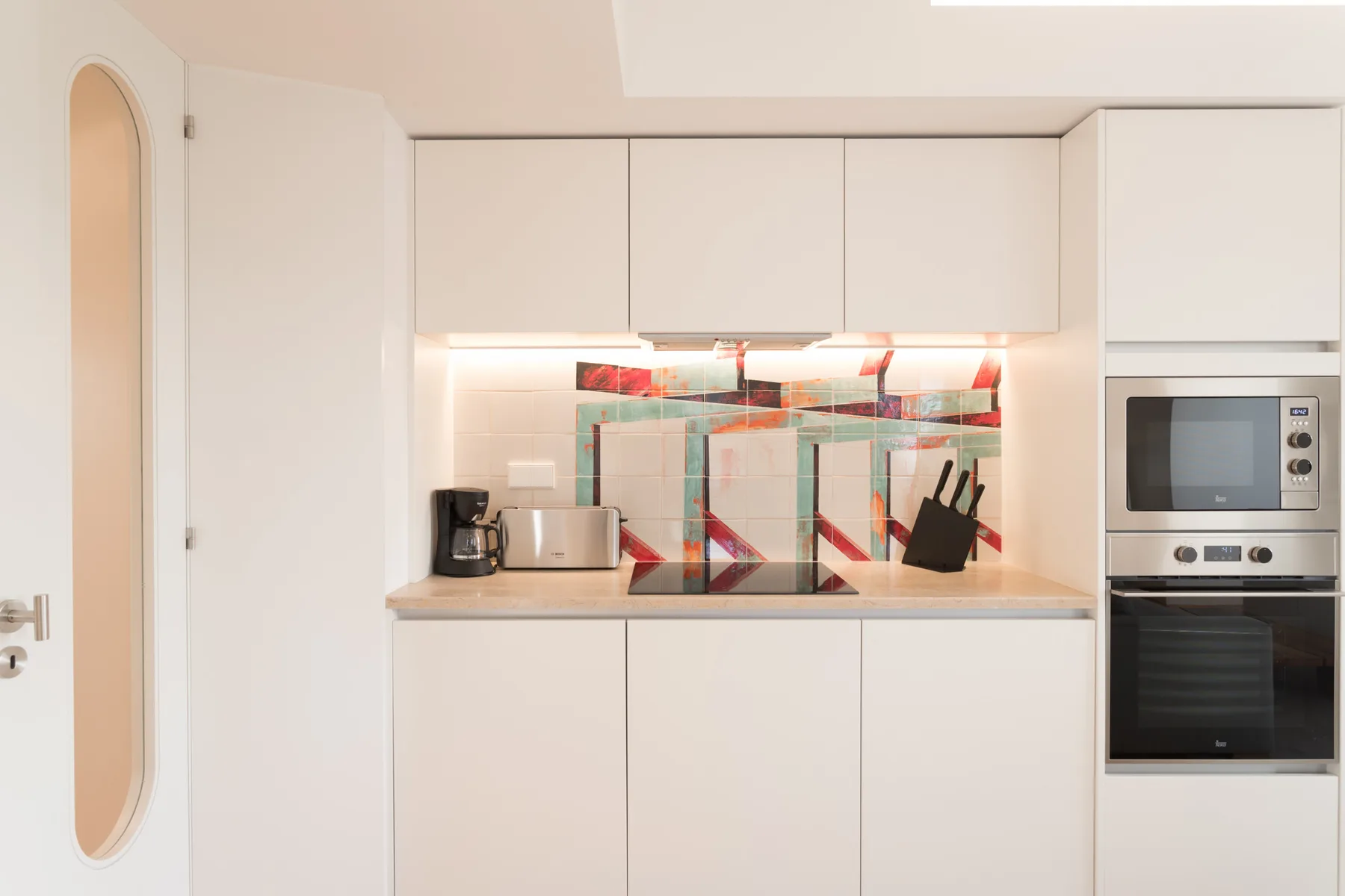 Una cocina moderna y luminosa con armarios blancos y un horno empotrado.