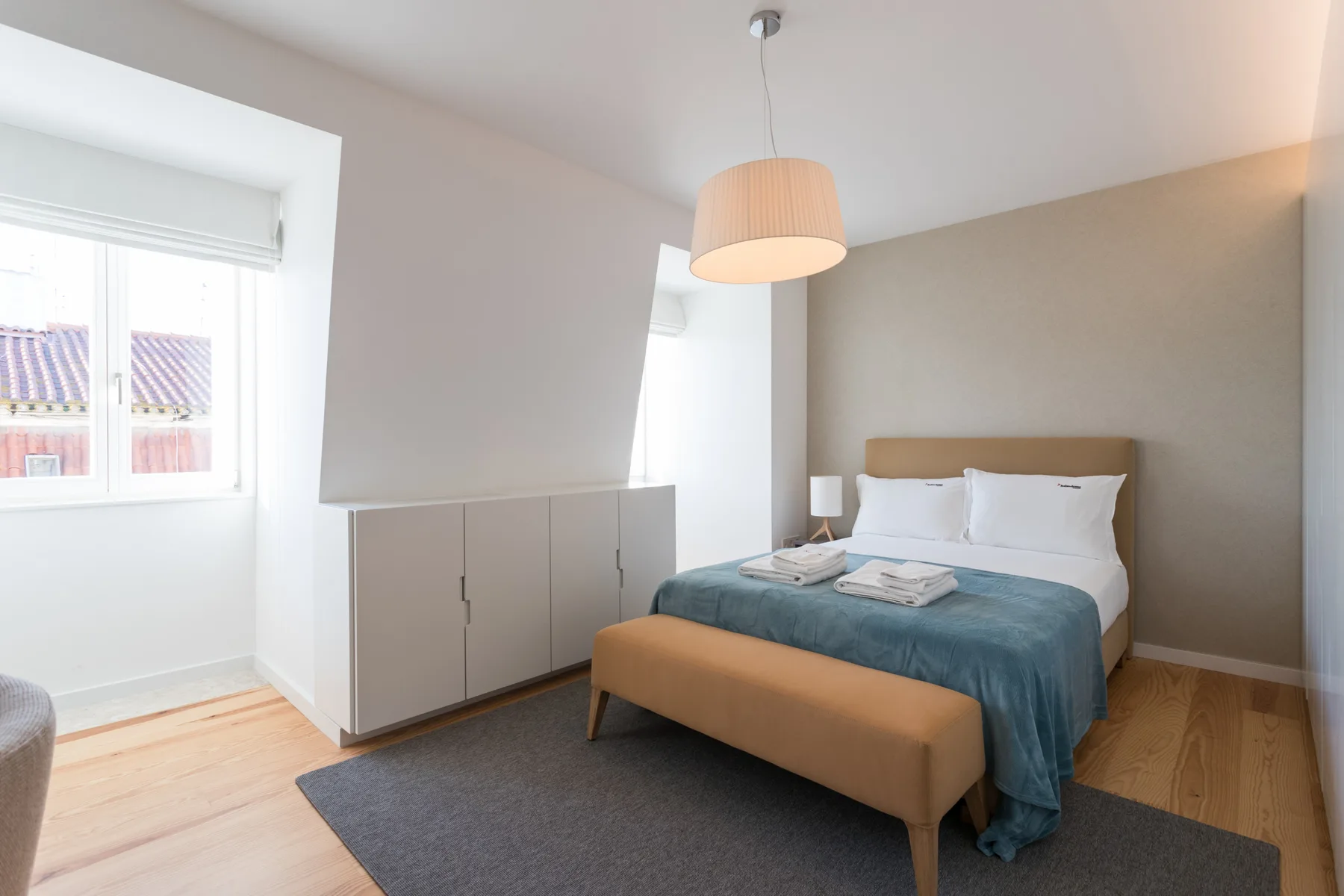 Dormitorio con cama doble, ropa de cama azul y una ventana.