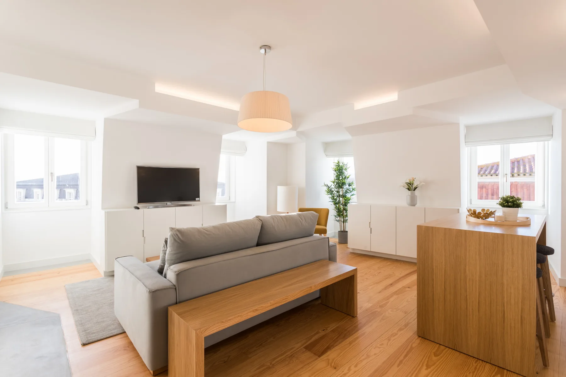 Sala de estar luminosa con asientos, un televisor y una mesa de comedor.