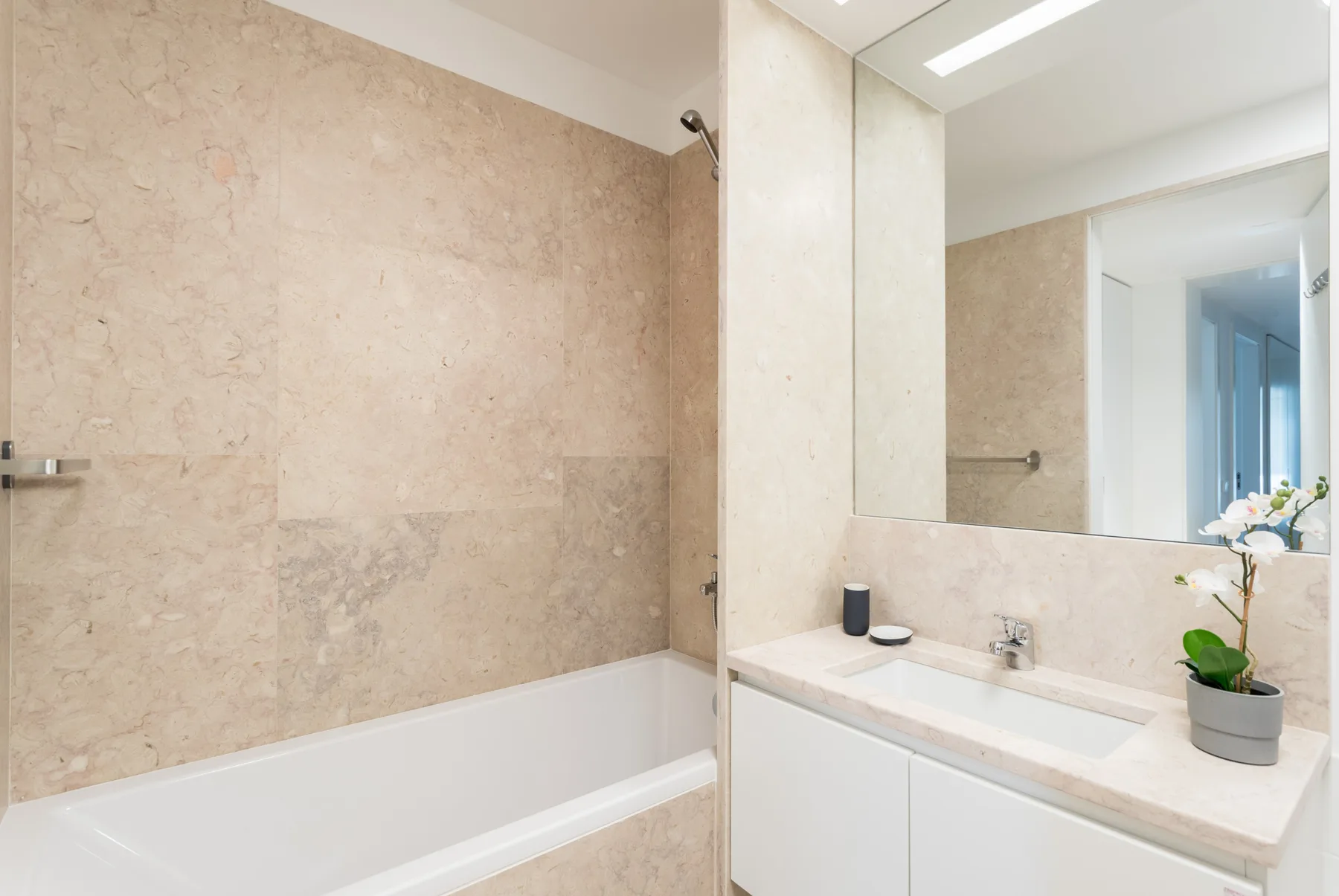 Un baño con bañera y lavabo bajo un espejo grande.