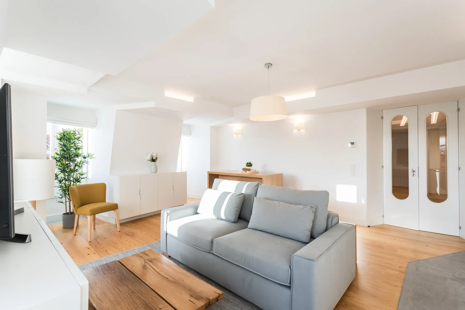 Un salón luminoso con sofá, mesa de centro y televisor.