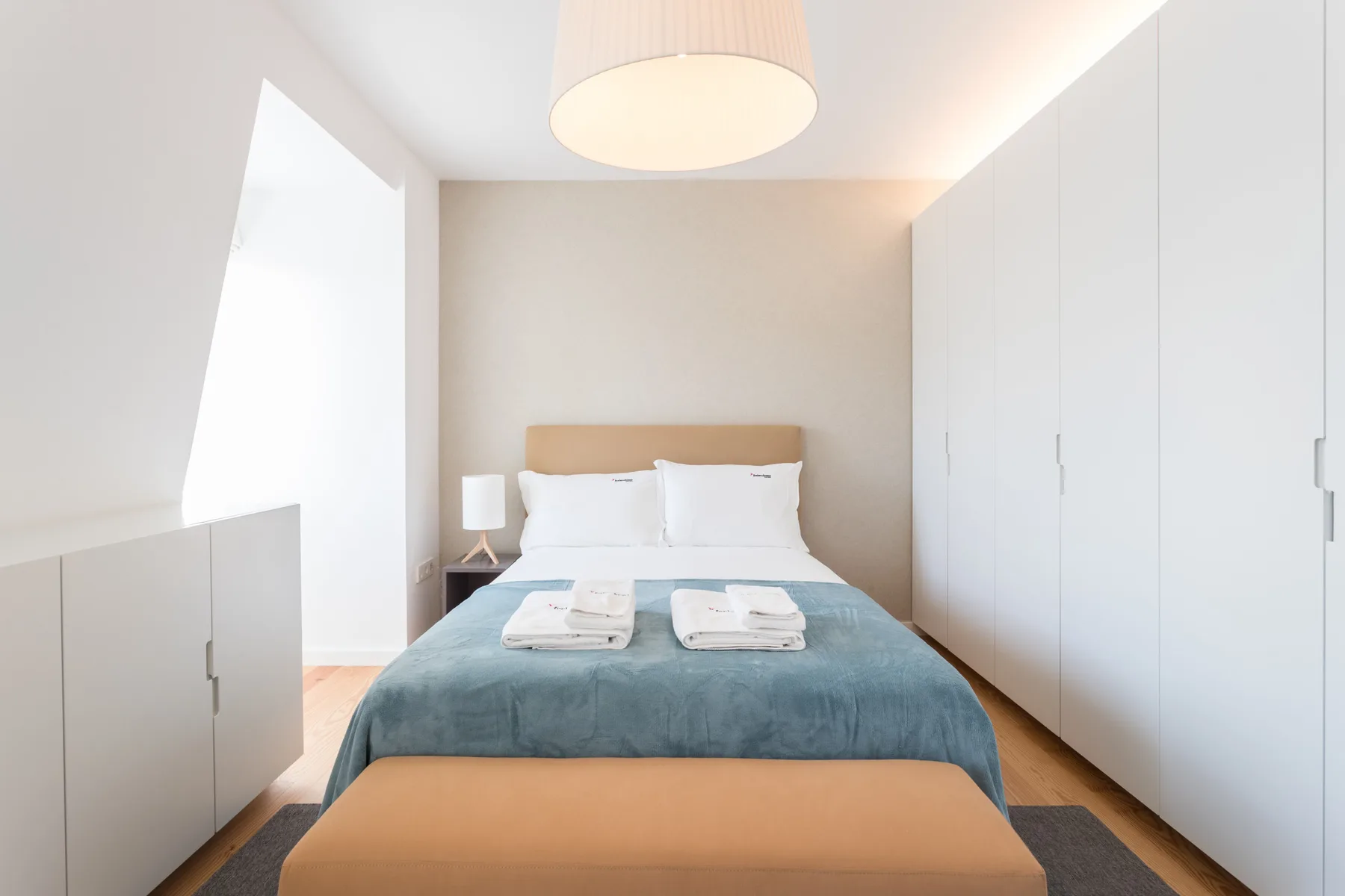 Un dormitorio luminoso con una cama y armarios empotrados blancos.