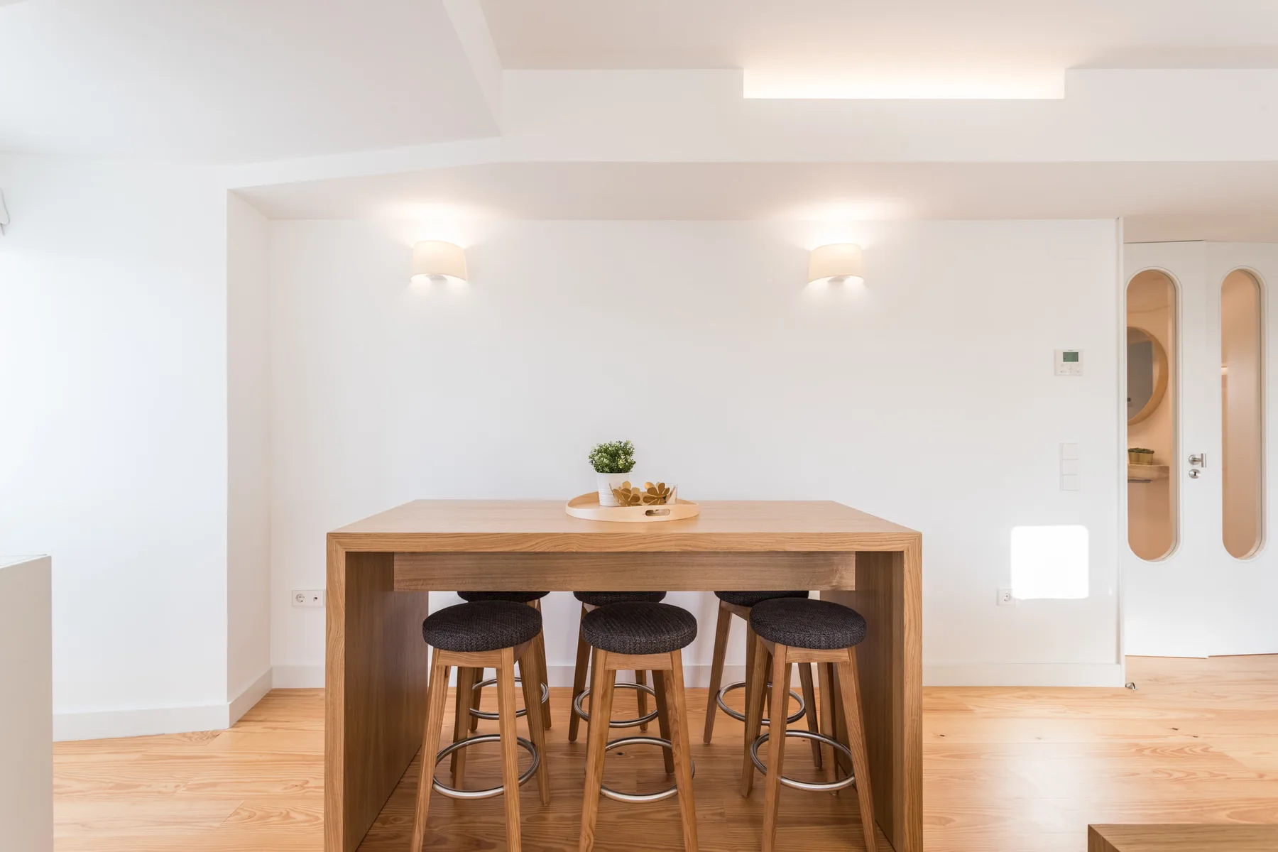 Un comedor luminoso con una mesa de madera y taburetes.