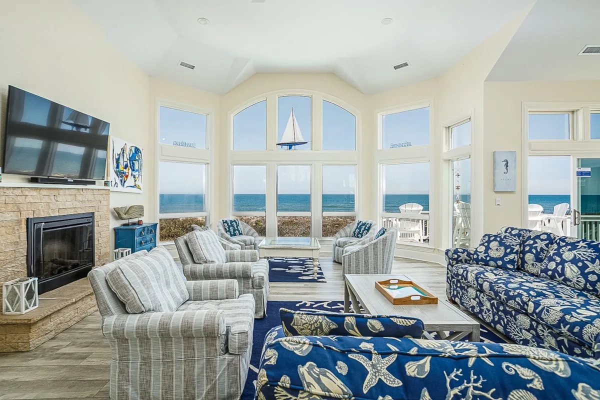 Una luminosa sala de estar con asientos estampados y amplias ventanas con vistas al mar.