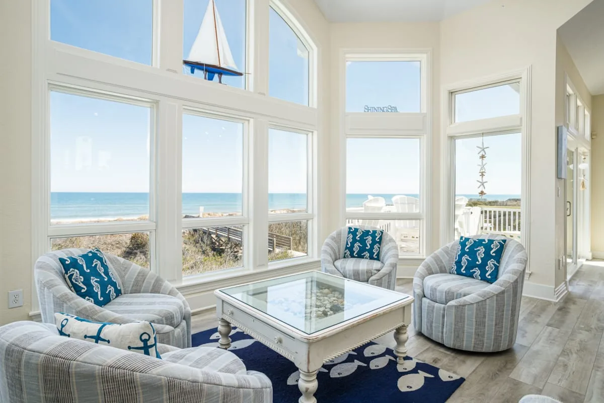 Una luminosa sala de estar con grandes ventanas que dan al mar.