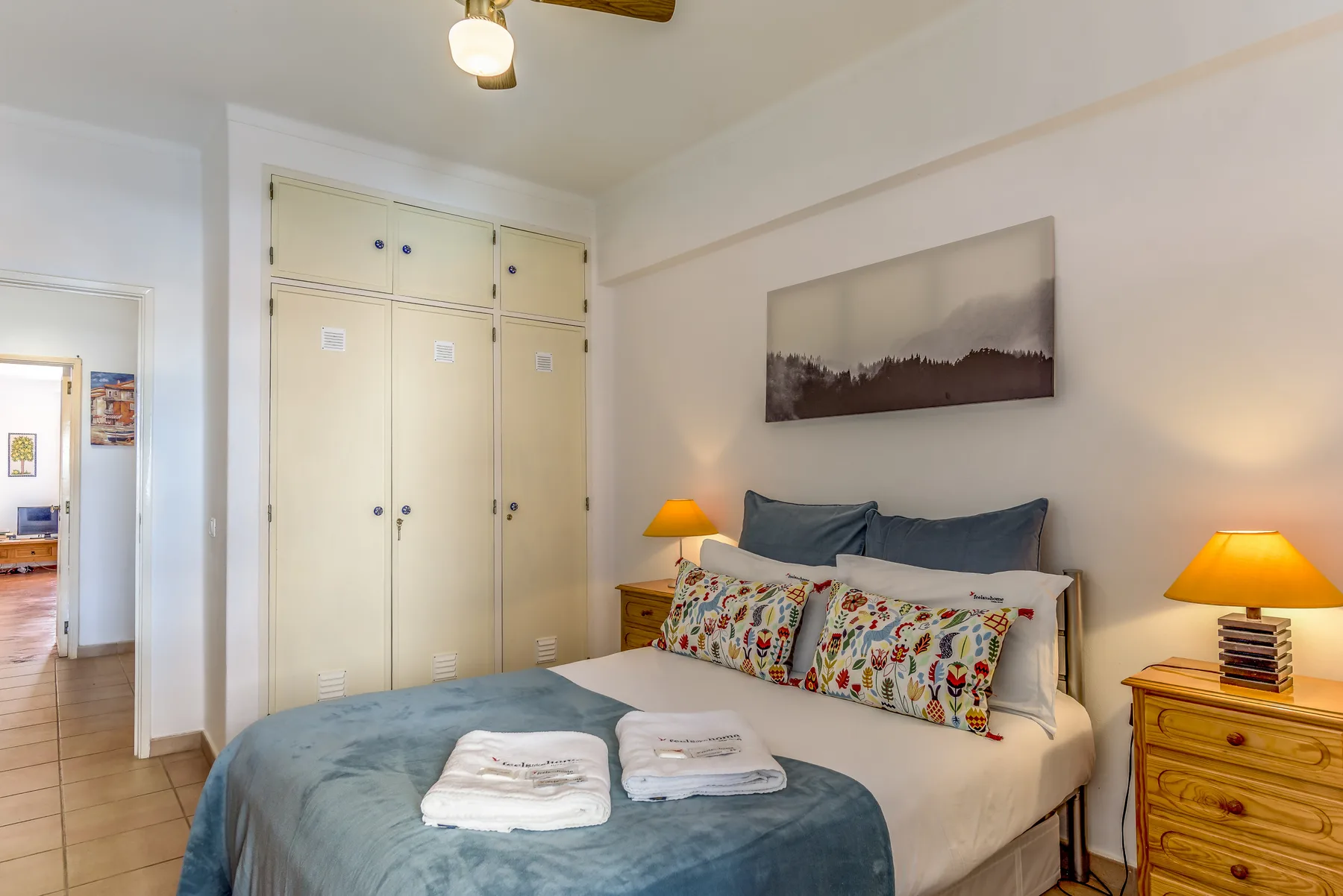 Un dormitorio con una cama, mesitas de noche y armarios empotrados.
