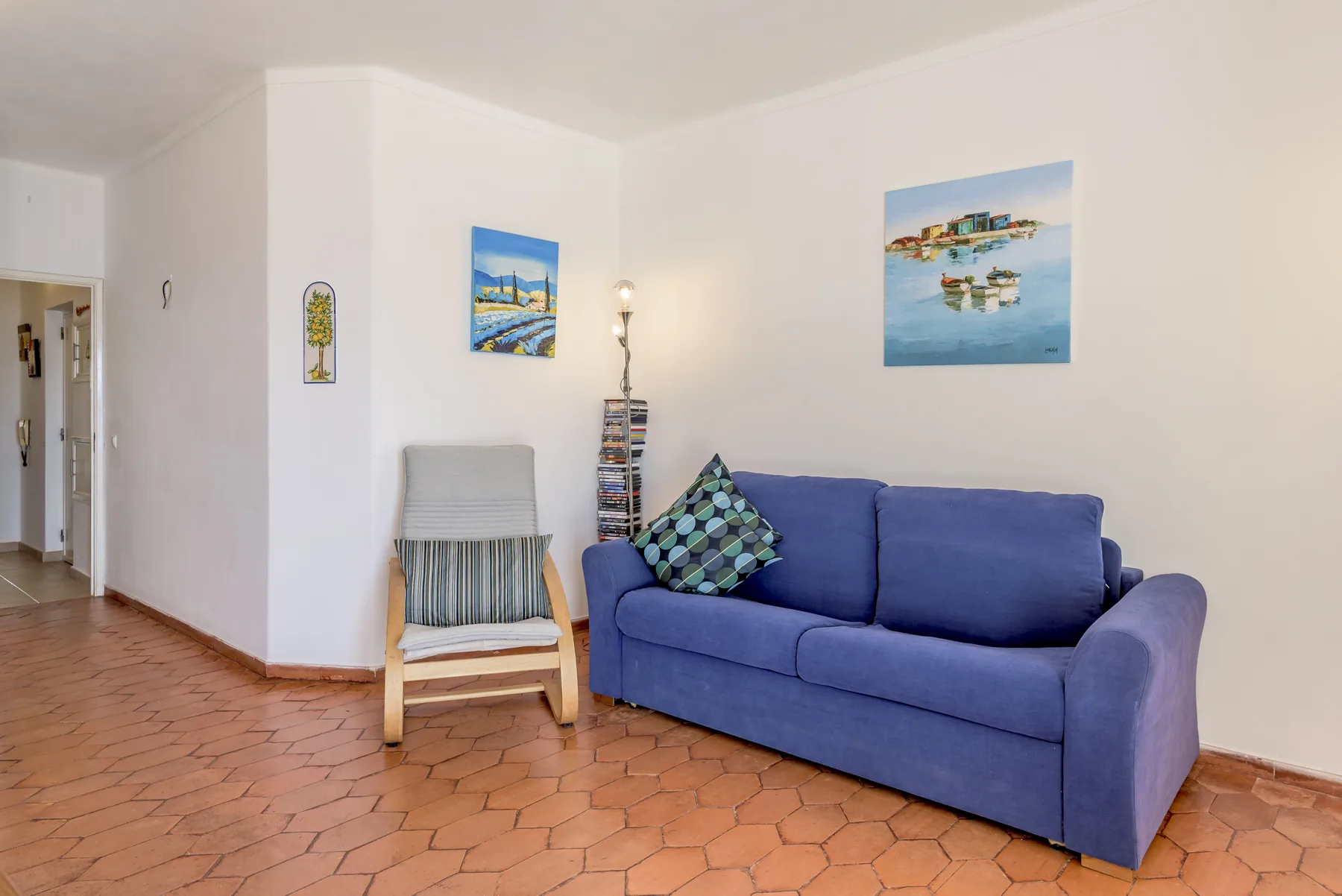 Una sala de estar con asientos azules y cuadros coloridos en las paredes.