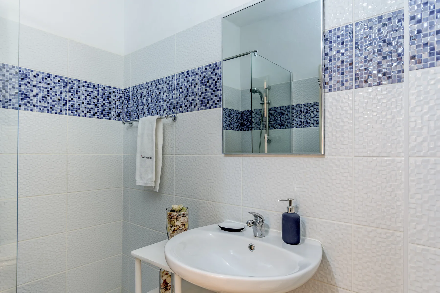 Un baño alicatado con lavabo, espejo y ducha.