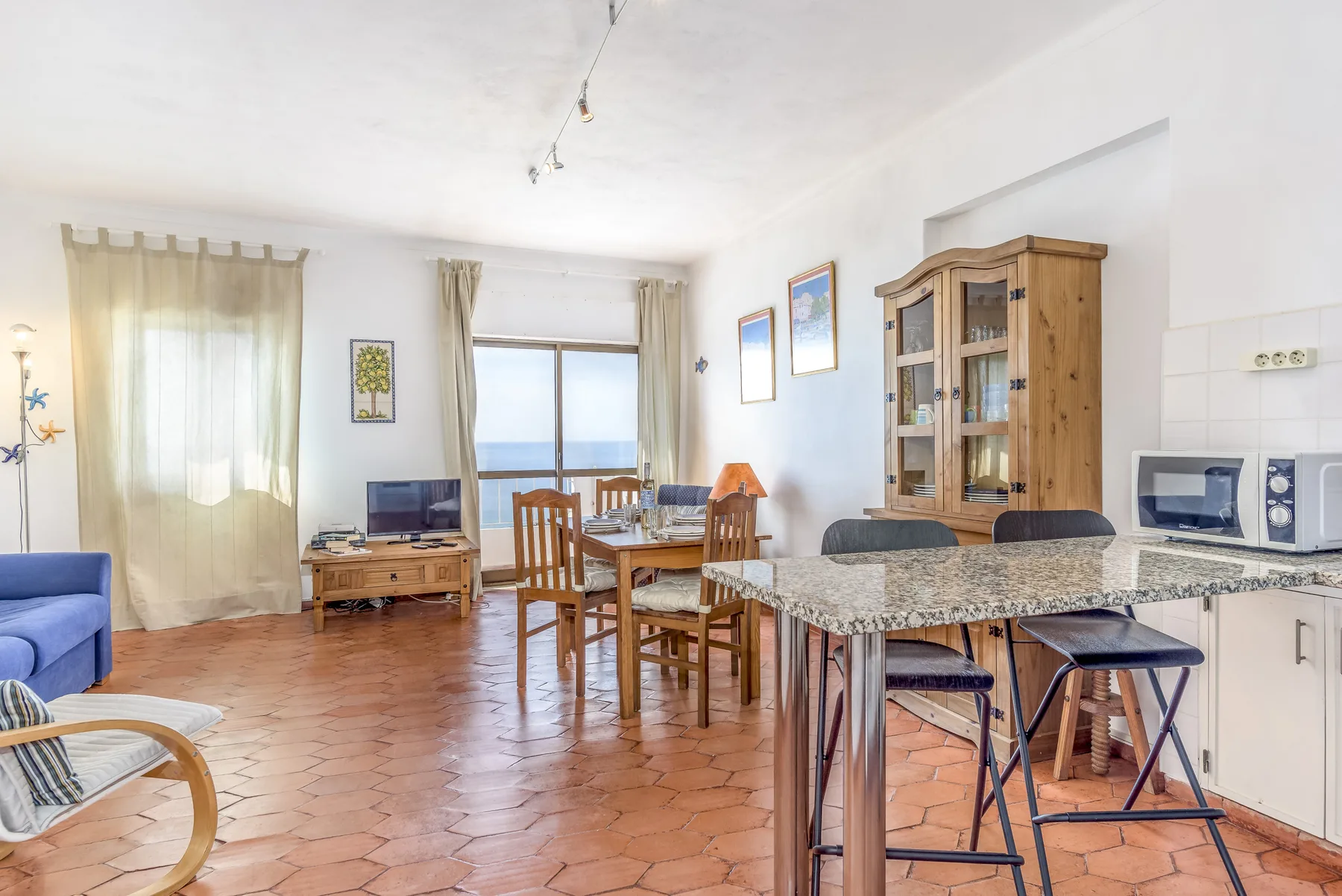 Una luminosa sala de estar y comedor da a un balcón, con mesa de comedor y barra de cocina.