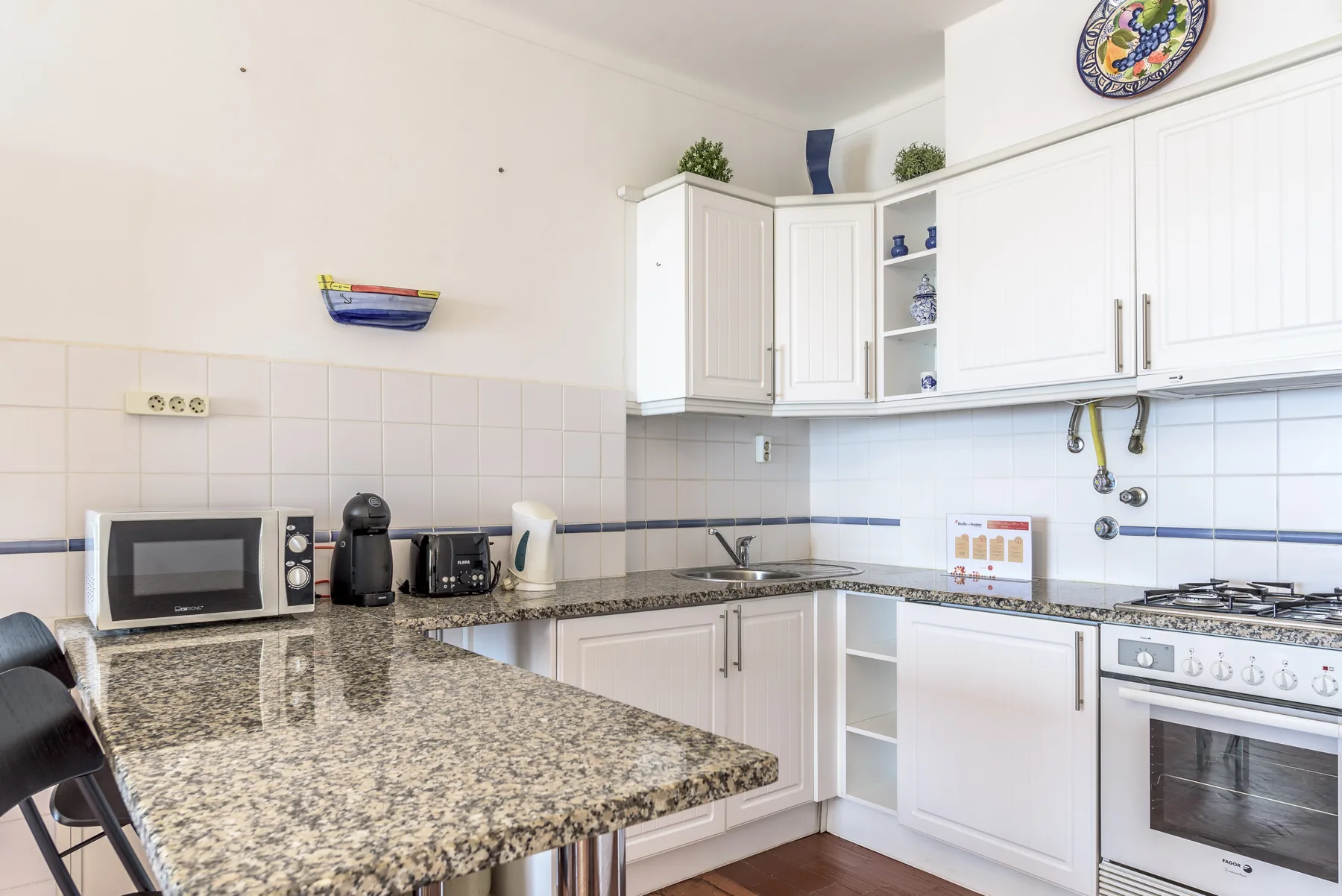 Una cocina luminosa con armarios blancos, encimera y electrodomésticos.