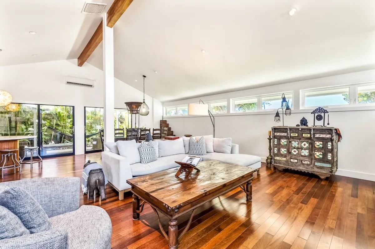 Una sala luminosa con un sofá seccional blanco y una mesa de centro de madera.