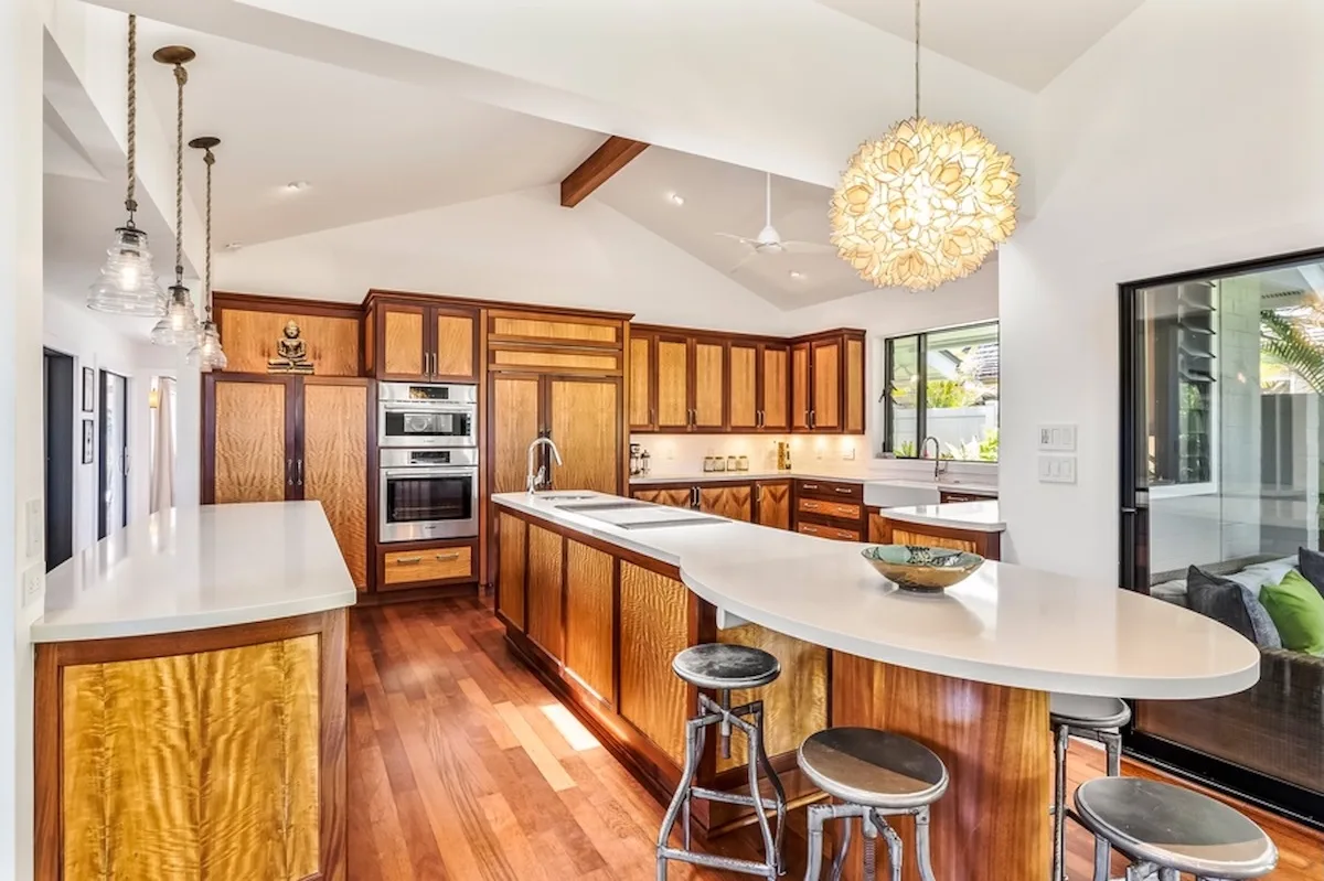 Una cocina luminosa con gabinetes de madera, encimeras blancas y una isla central.