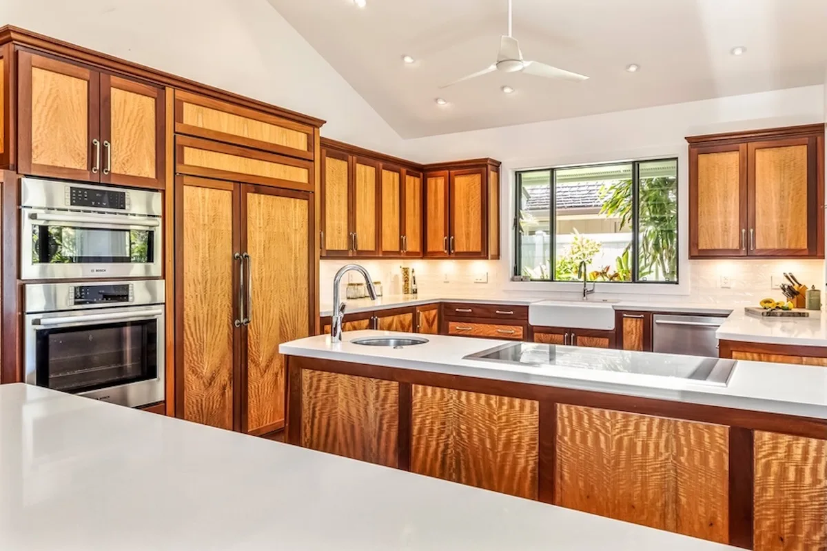 Una cocina amplia con gabinetes de madera, encimeras blancas y una isla grande.