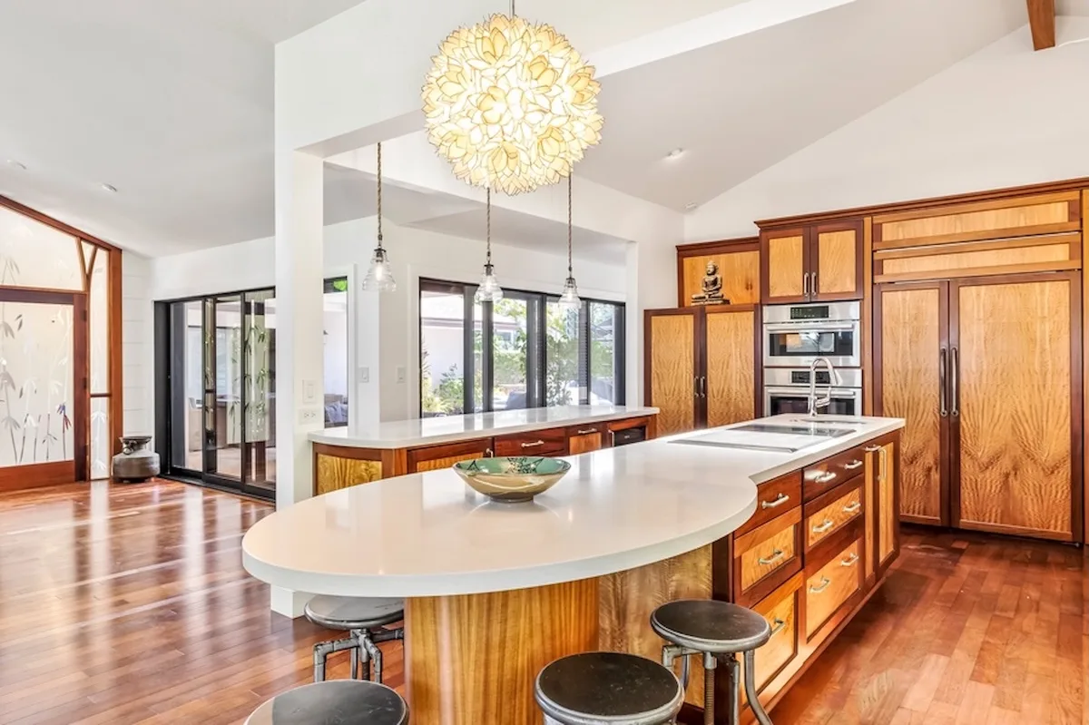 Una cocina luminosa con una gran isla, gabinetes de madera y luces colgantes.