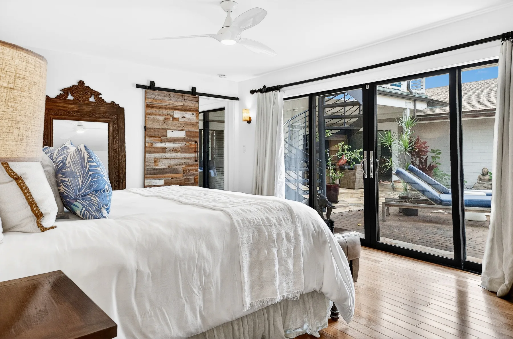 Un dormitorio luminoso con una cama junto a puertas de vidrio que dan a un patio.