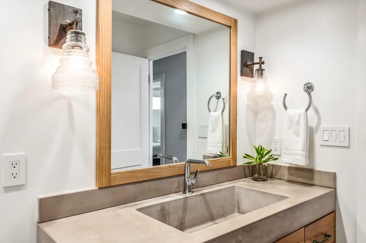 Un tocador de baño con un espejo grande, lavabo y toalleros.