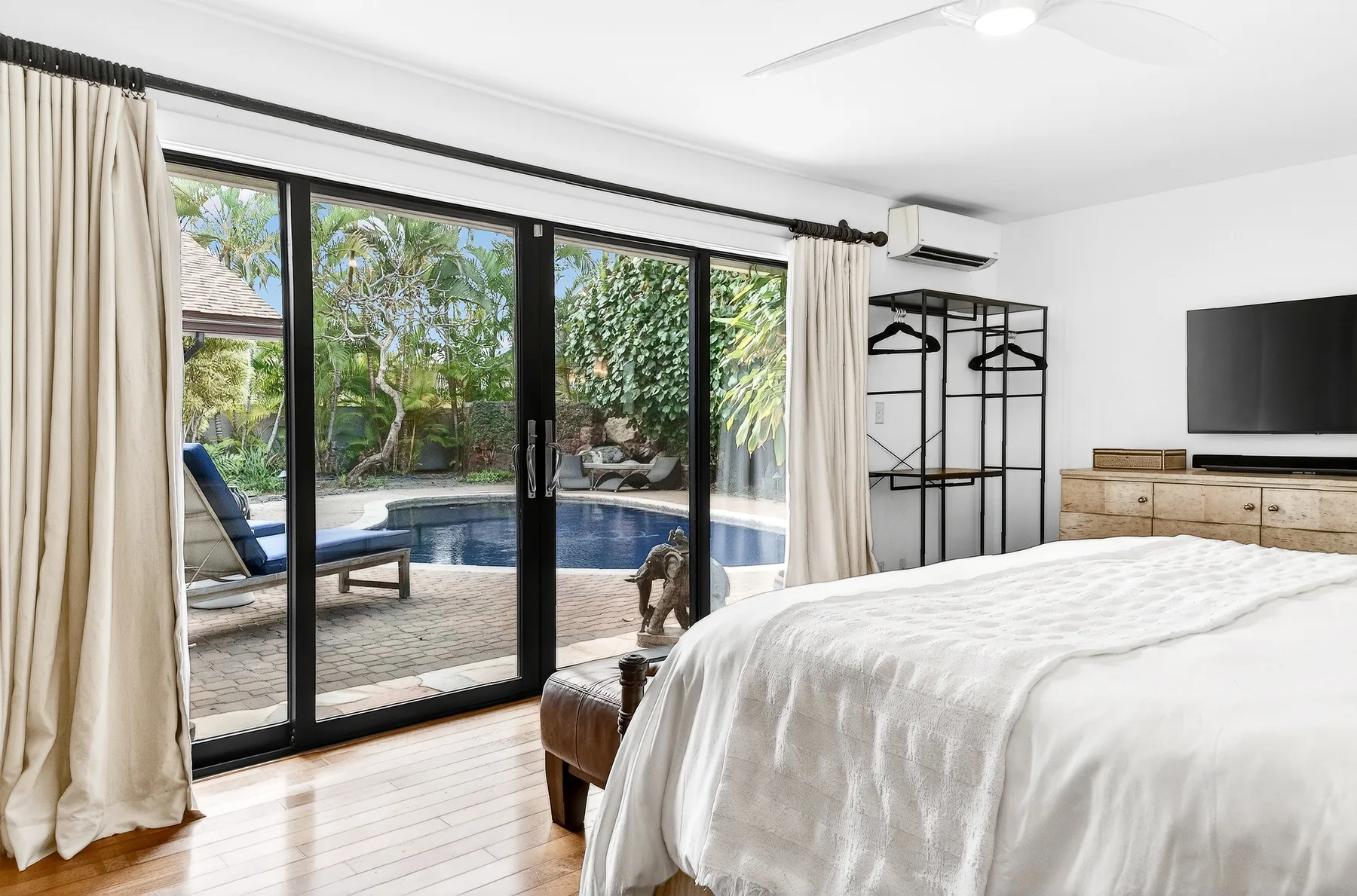 Un dormitorio da a un patio con piscina y jardín.