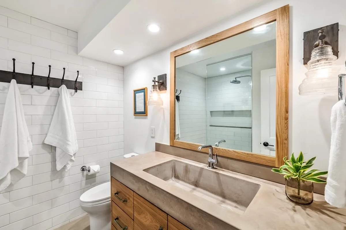 Un baño luminoso con un tocador largo, lavabo y un espejo grande.
