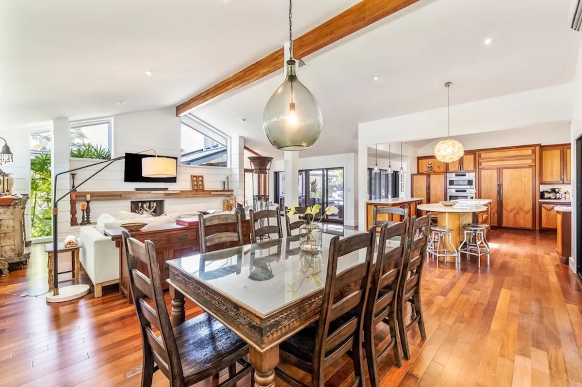 Un espacio abierto de comedor y cocina con una mesa grande y gabinetes de madera.