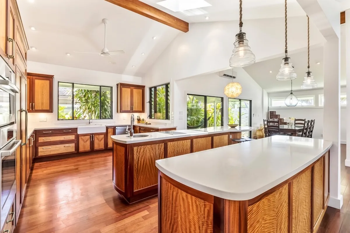 Una cocina luminosa con gabinetes de madera, amplias encimeras y ventanas con vista a la vegetación.