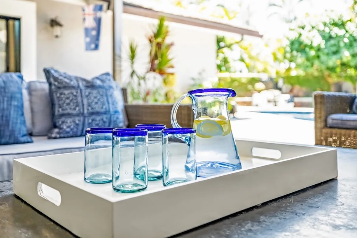 Una luminosa zona de estar al aire libre con una bandeja de vasos y una jarra.