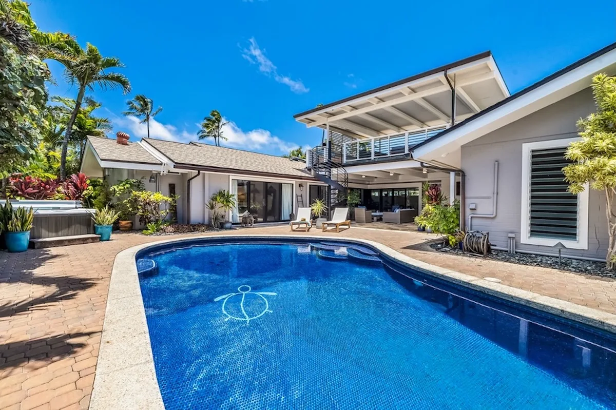 Una piscina está en el patio junto a una casa moderna y una terraza.