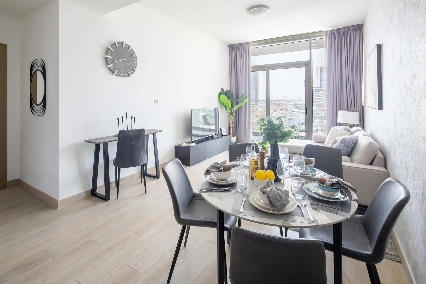 Una luminosa sala de estar y comedor con la mesa puesta junto a una ventana grande.