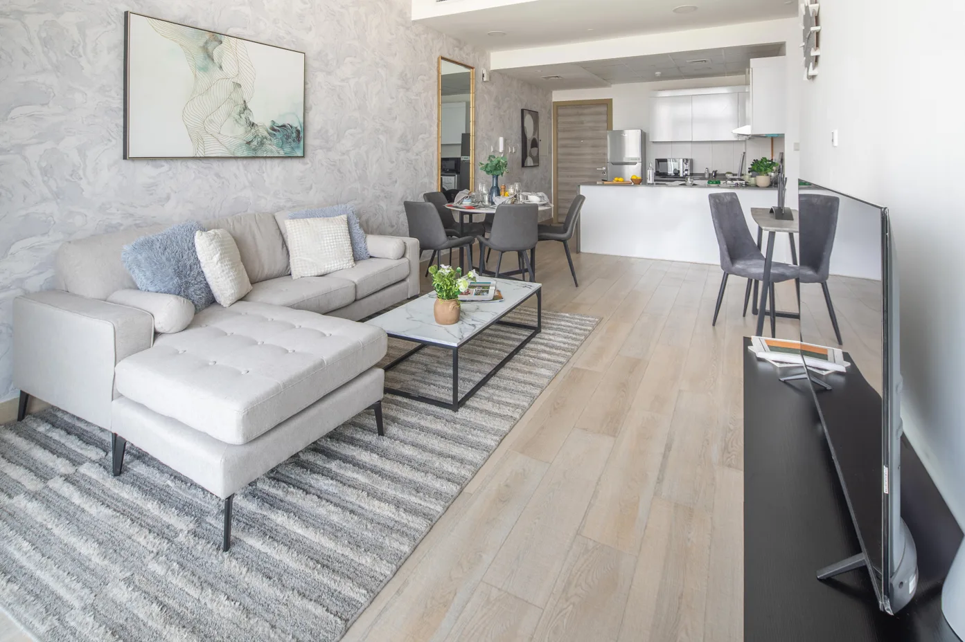 Una sala de estar y cocina de planta abierta con sofá seccional y mesa de comedor.