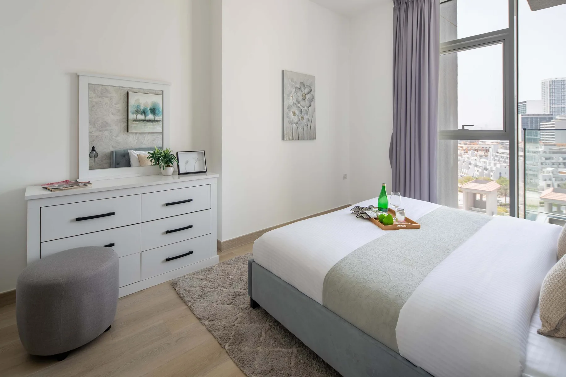 Un dormitorio luminoso con una cama bien hecha junto a una ventana grande.