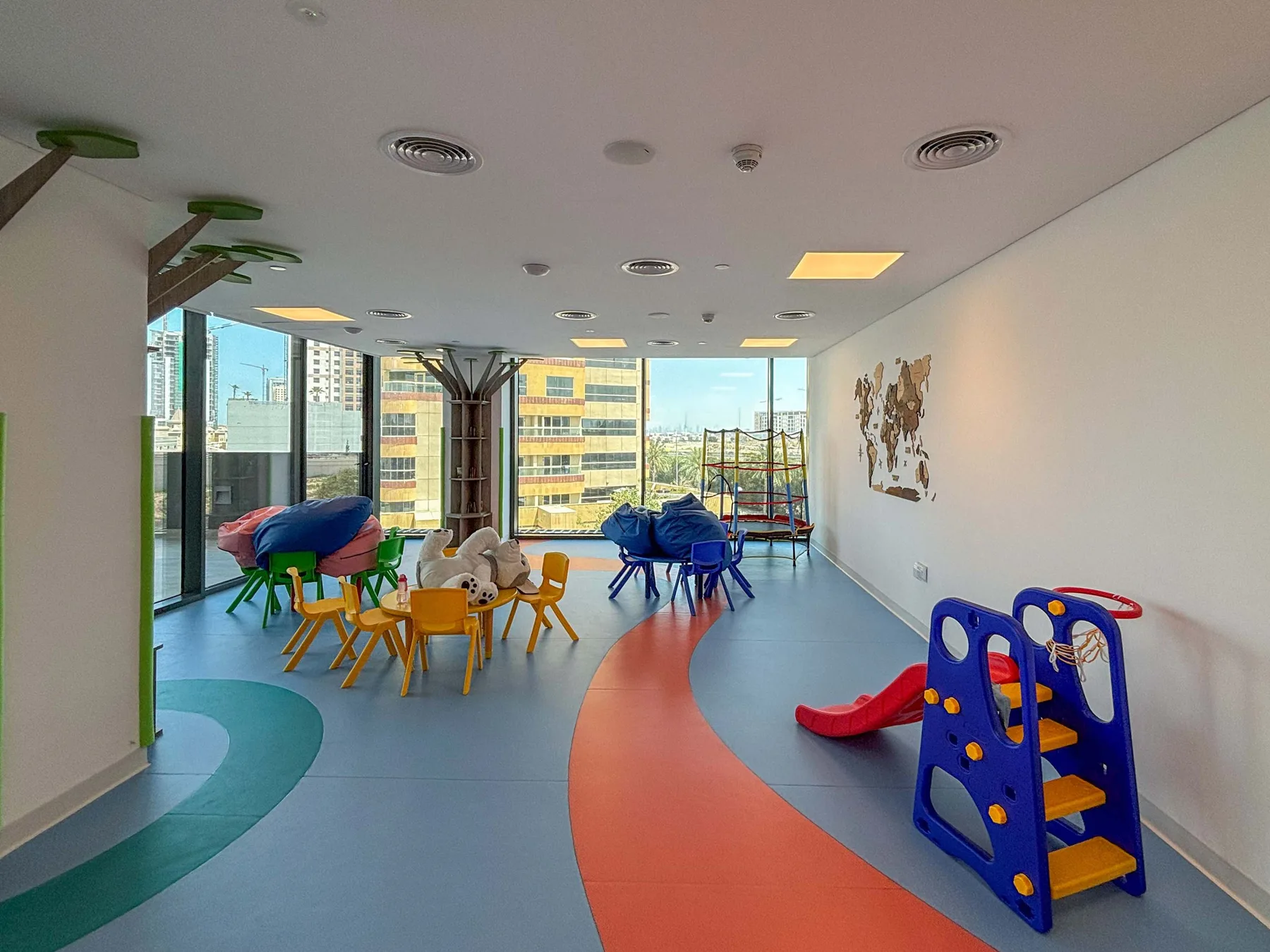 Una sala de juegos luminosa tiene asientos coloridos, juegos y ventanales.