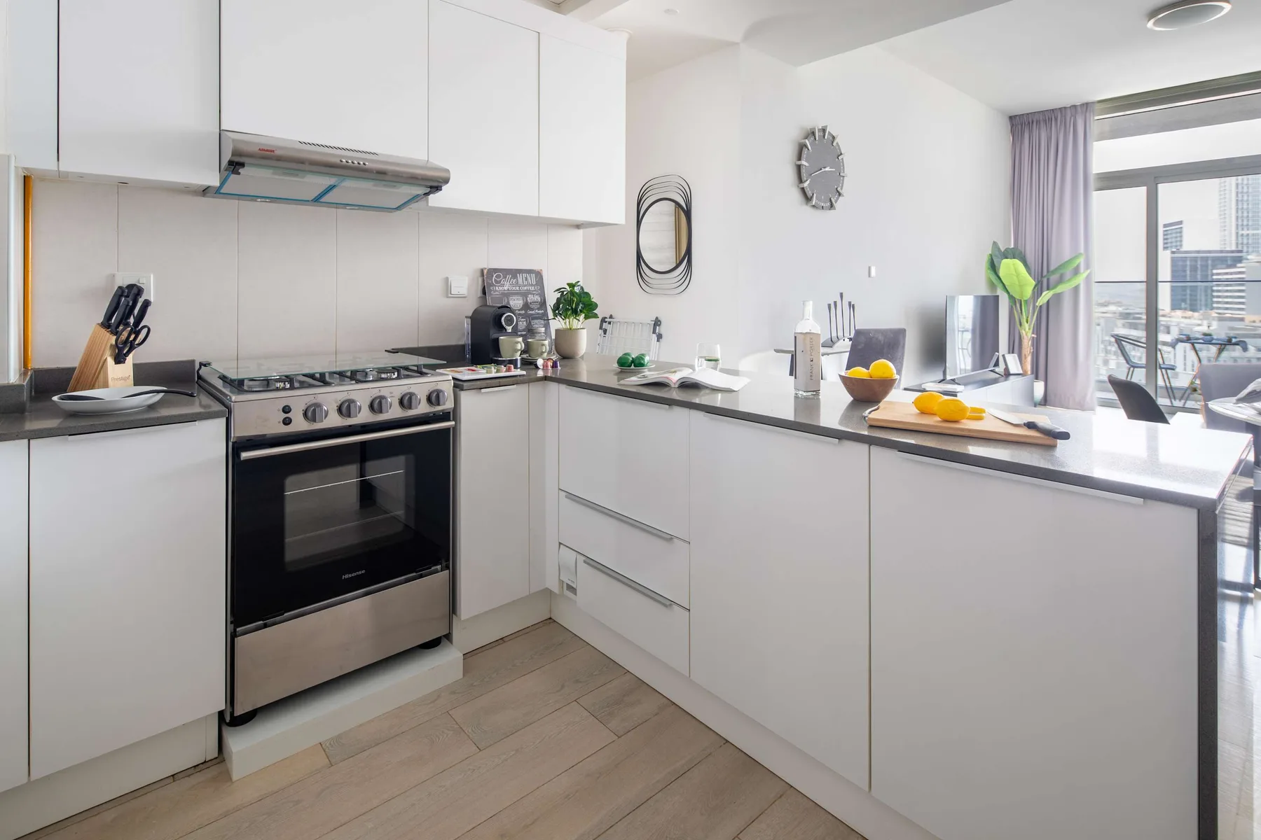 Una cocina moderna y luminosa con gabinetes blancos y una barra.