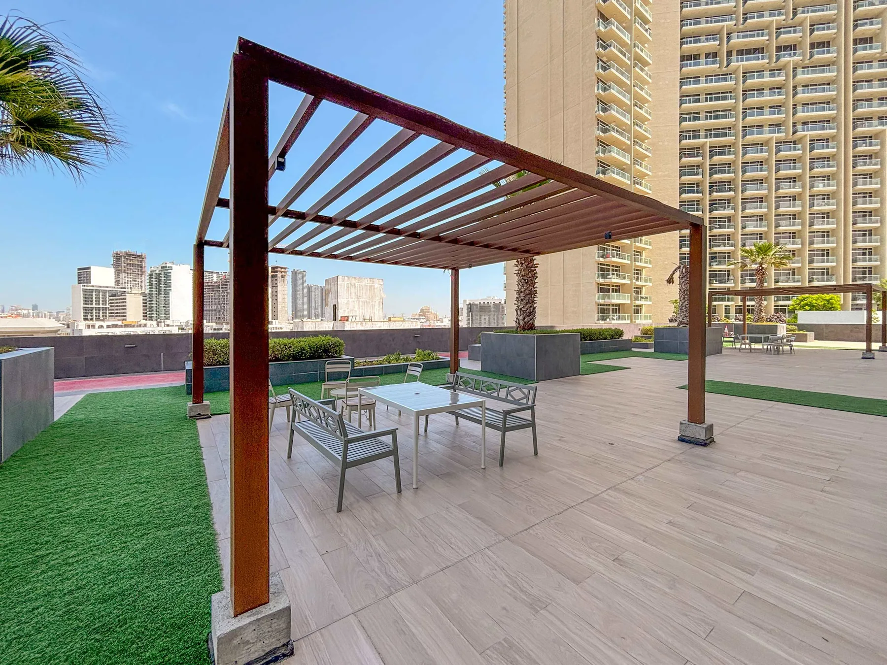 Una terraza en la azotea con asientos al aire libre bajo una pérgola.