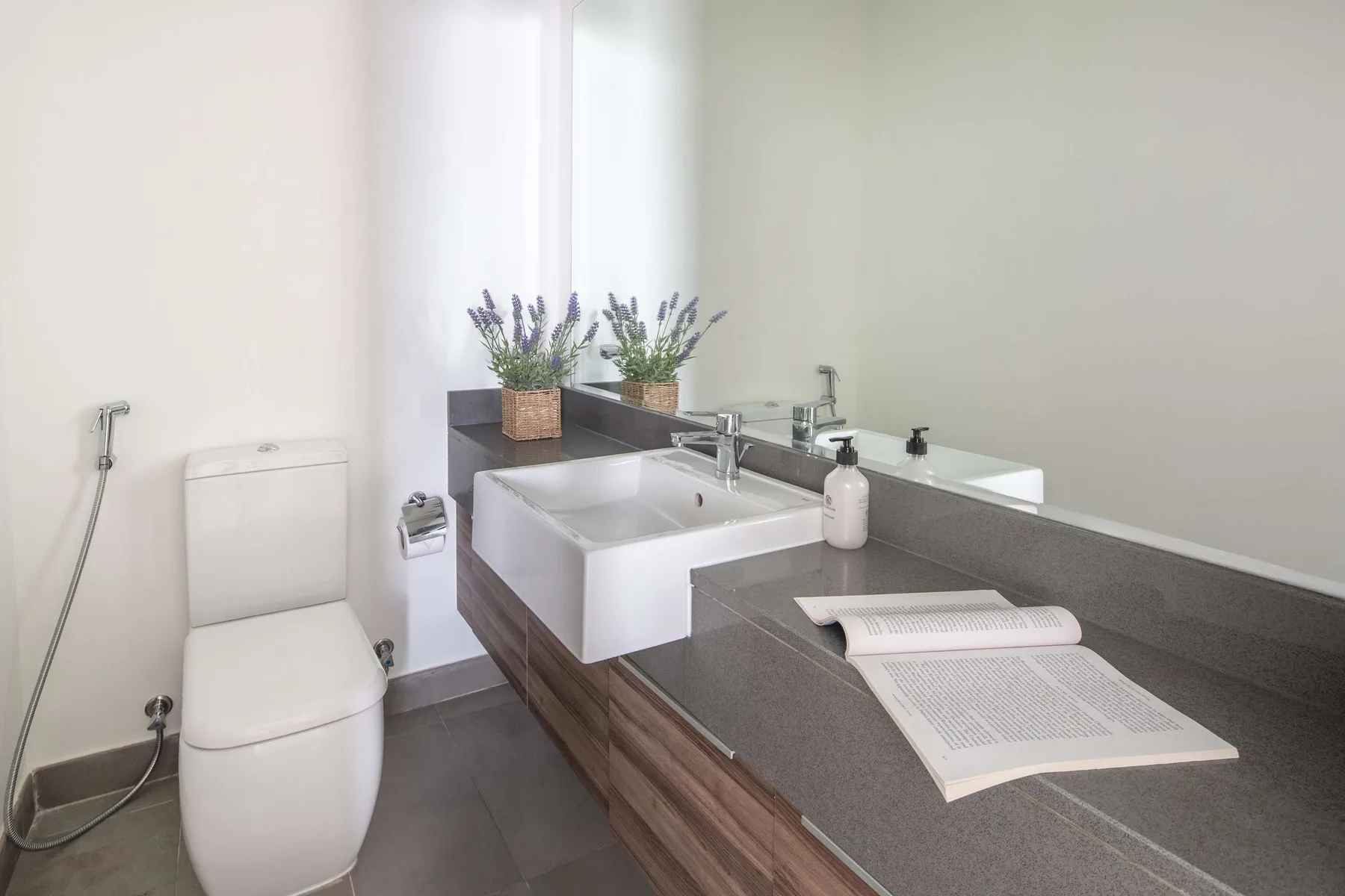 Un baño con un inodoro, un lavabo y un libro abierto sobre la encimera.