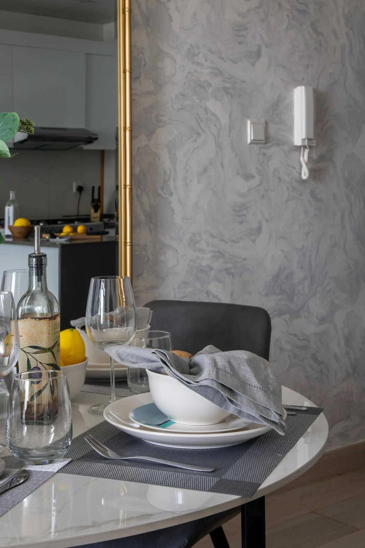 Una mesa de comedor está puesta con platos y vasos junto a una cocina.