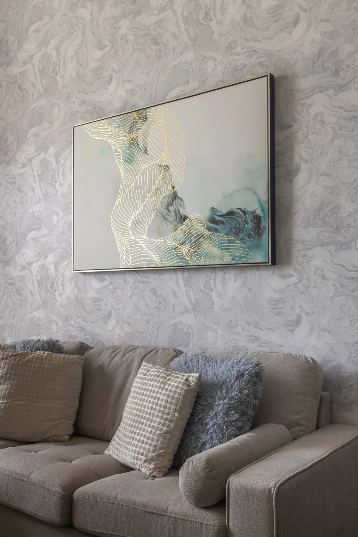 Una zona de estar con una obra abstracta enmarcada sobre el sofá.