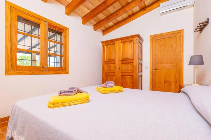 Un dormitorio con una cama grande, un armario de madera y vigas vistas en el techo.