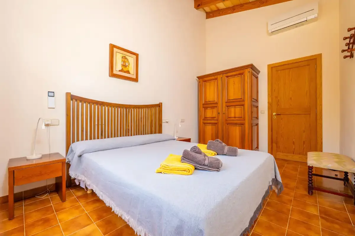 Un dormitorio con una cama, un armario de madera y suelo de baldosas.