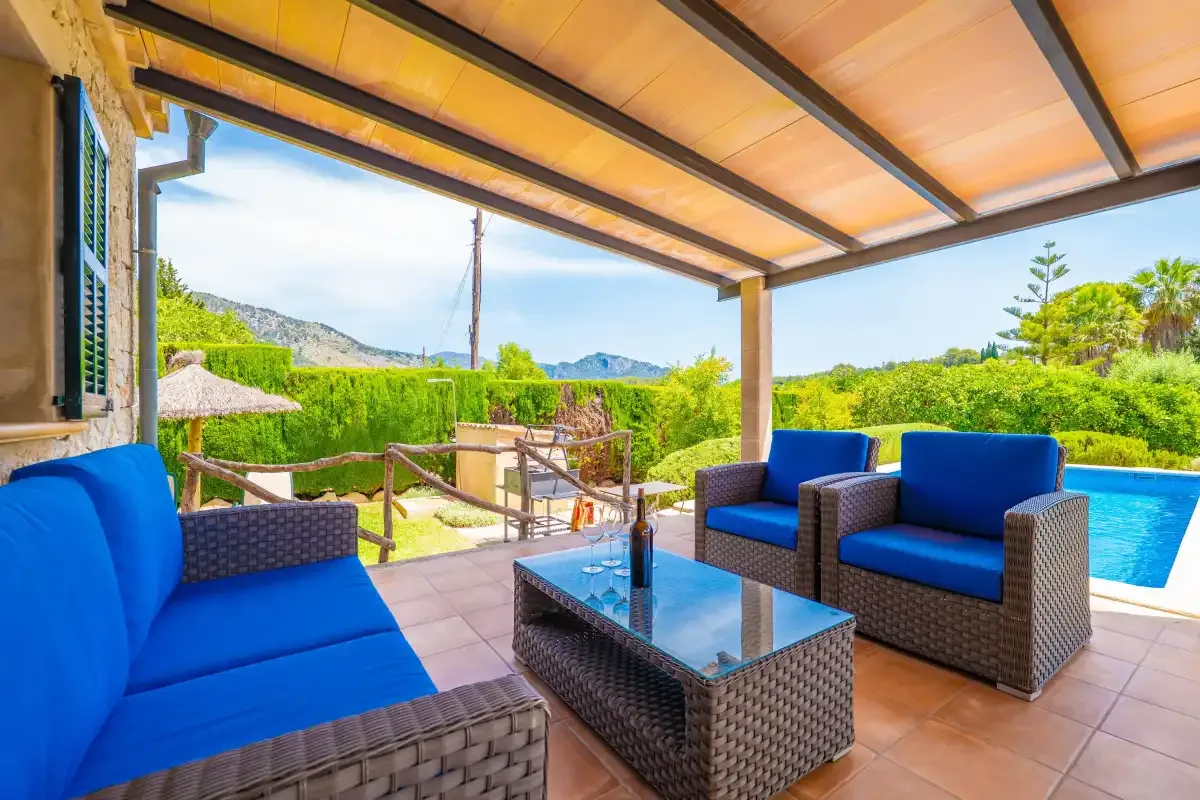 Una zona de estar exterior cubierta con cojines azules da a un jardín y una piscina.