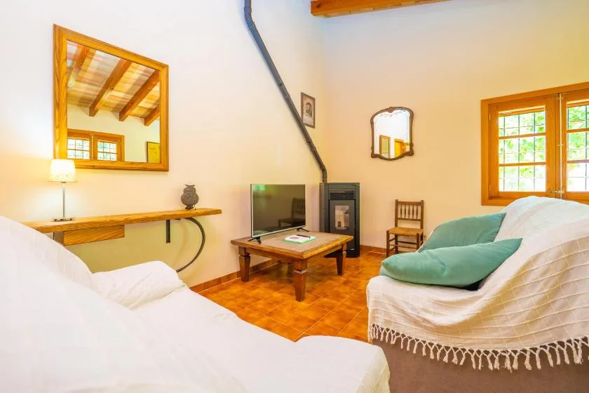 Una sala luminosa con asientos, un televisor y una ventana con marco de madera.