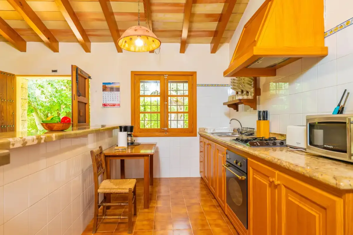 Una cocina con gabinetes de madera, encimeras de azulejos y una pequeña mesa de comedor.