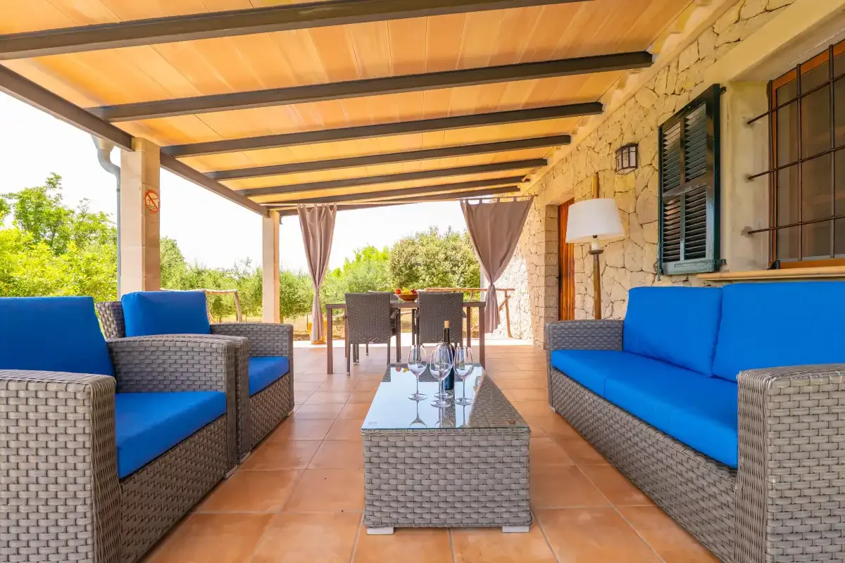 Una zona de estar exterior cubierta con una mesa y asientos con cojines azules.