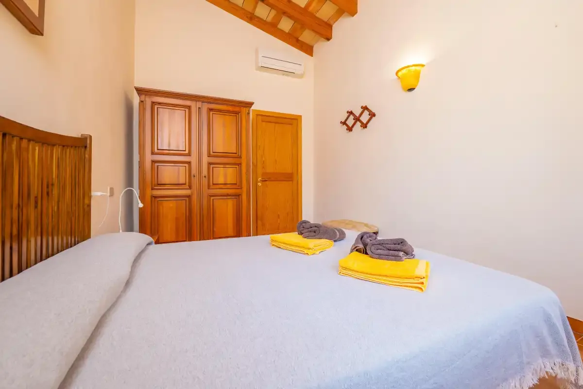 Un dormitorio con una cama y puertas de madera bajo un techo inclinado.
