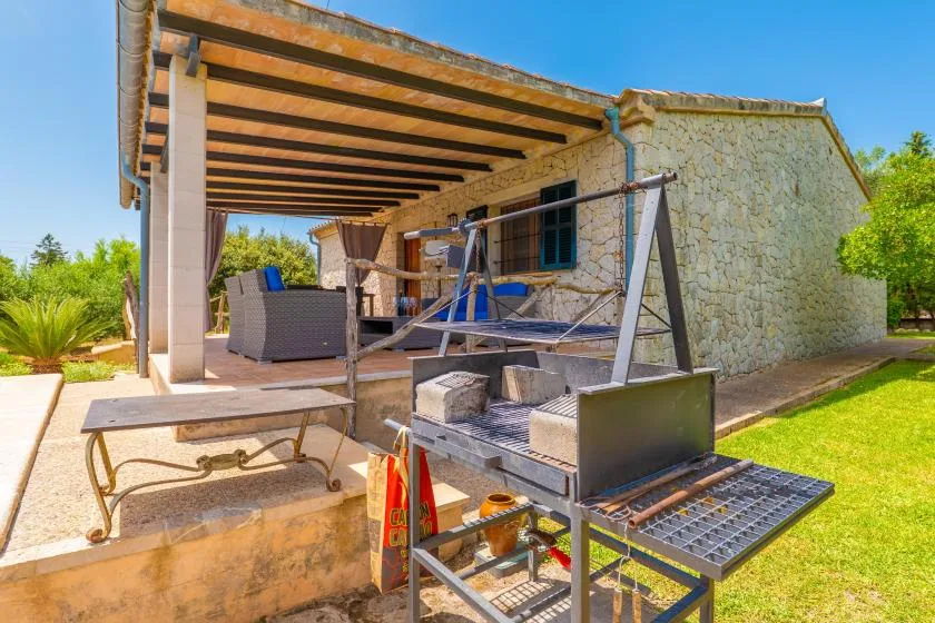 Un patio exterior cubierto con asientos y una parrilla junto a un edificio de piedra.