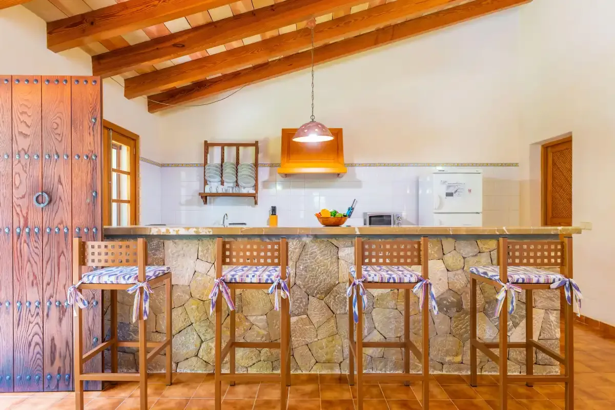 Una cocina con una barra revestida de piedra y taburetes de madera.