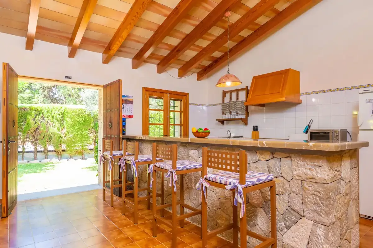 Una cocina y comedor con una barra de frente de piedra y asientos de madera.