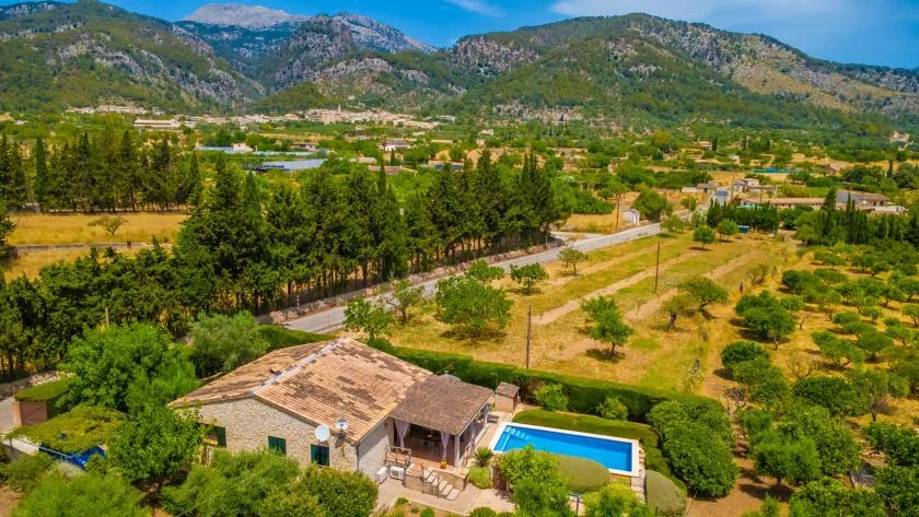 Una propiedad rural con piscina está rodeada de árboles al pie de una cordillera.