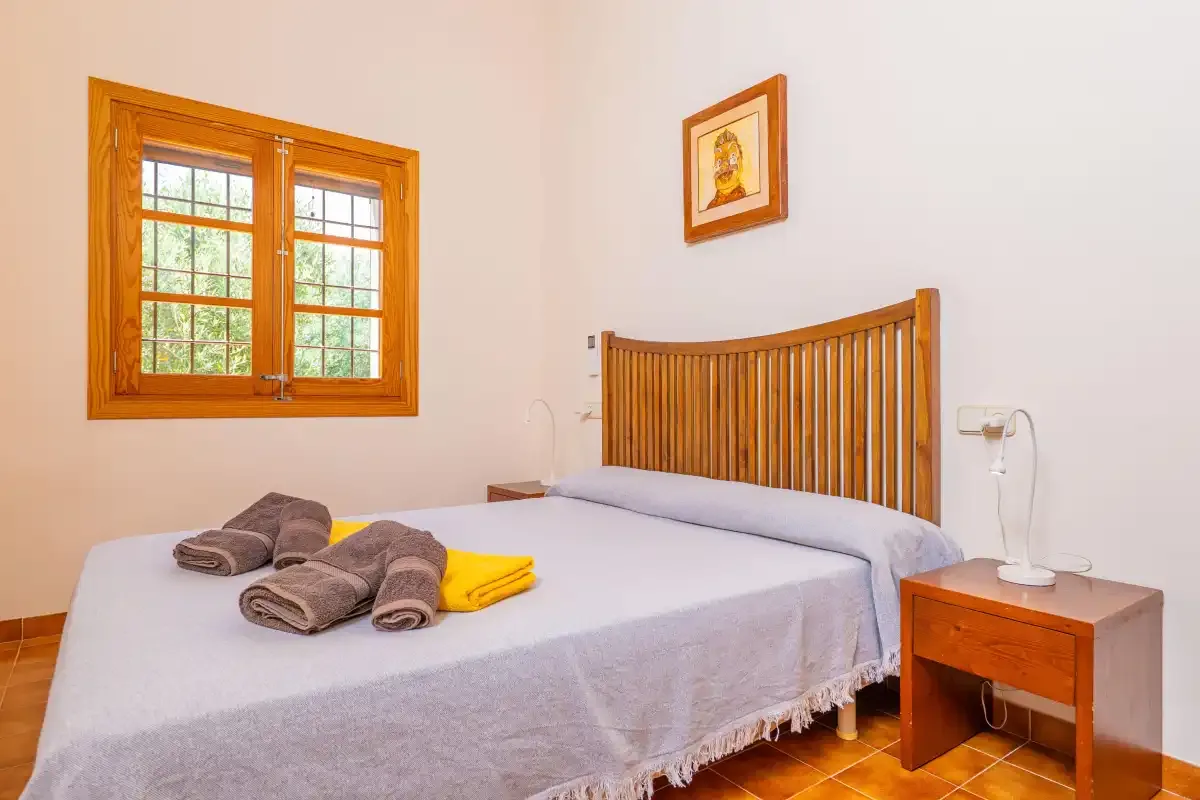 Un dormitorio con una cama, un cabecero de madera y una ventana.