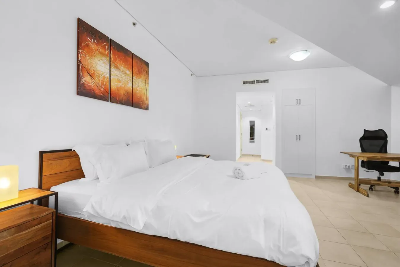 Un dormitorio con una cama grande, arte en la pared y un escritorio.