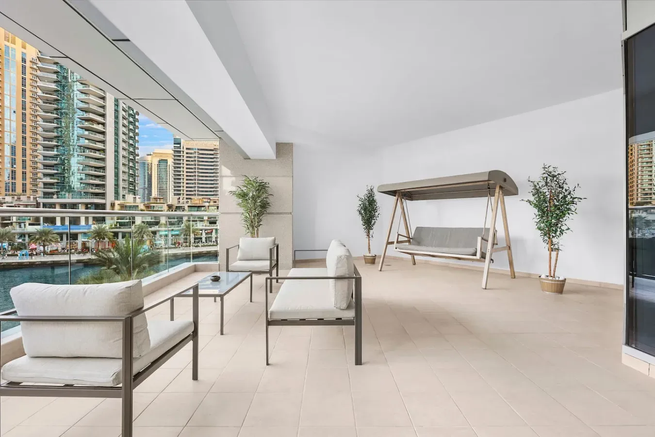 Una terraza luminosa con asientos, un columpio y vistas de edificios altos cercanos.